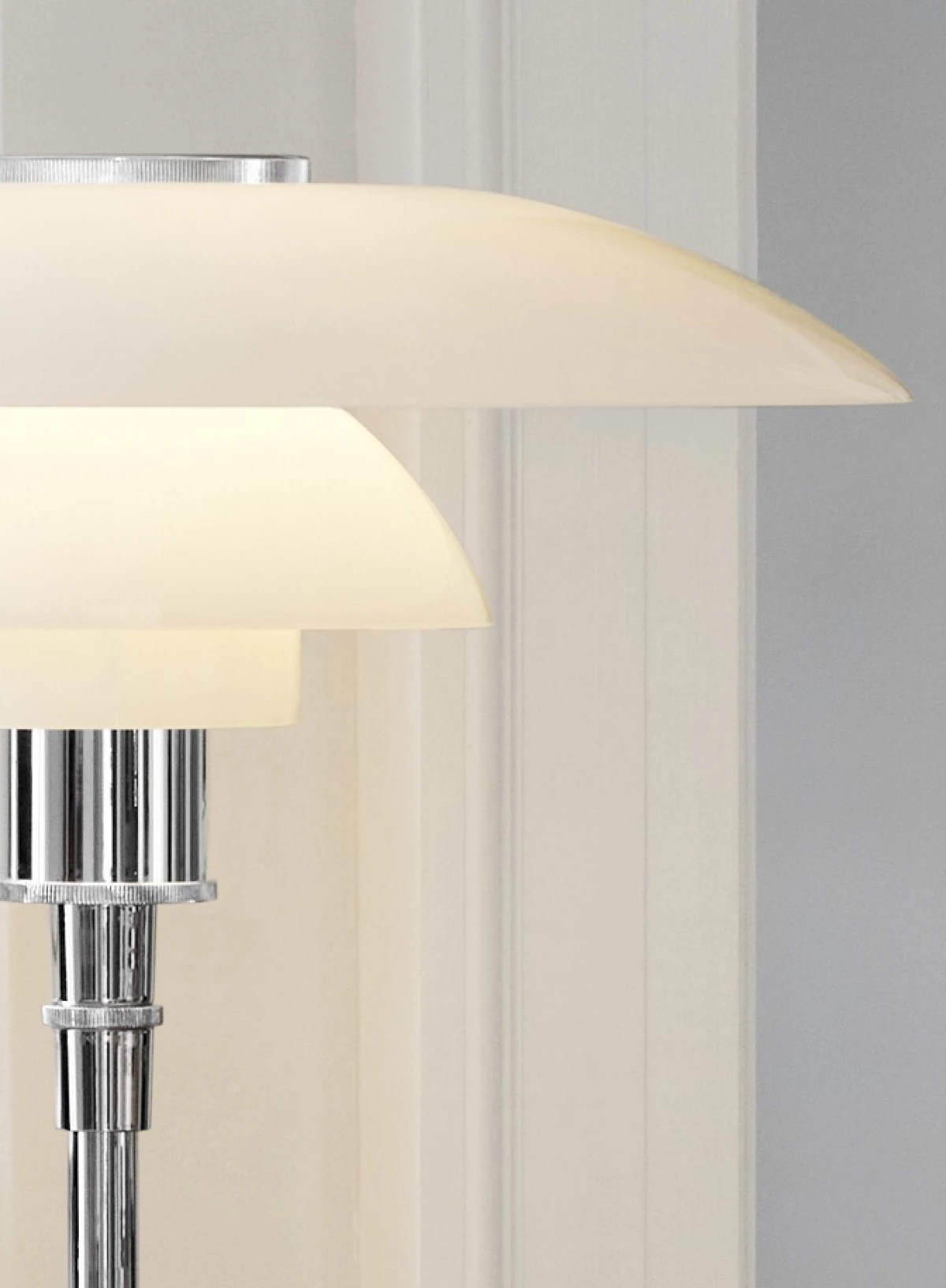 PH 4/3 Table Lamp in white opal glass and chrome, shown close up against a light wall. © 2026 Louis Poulsen.