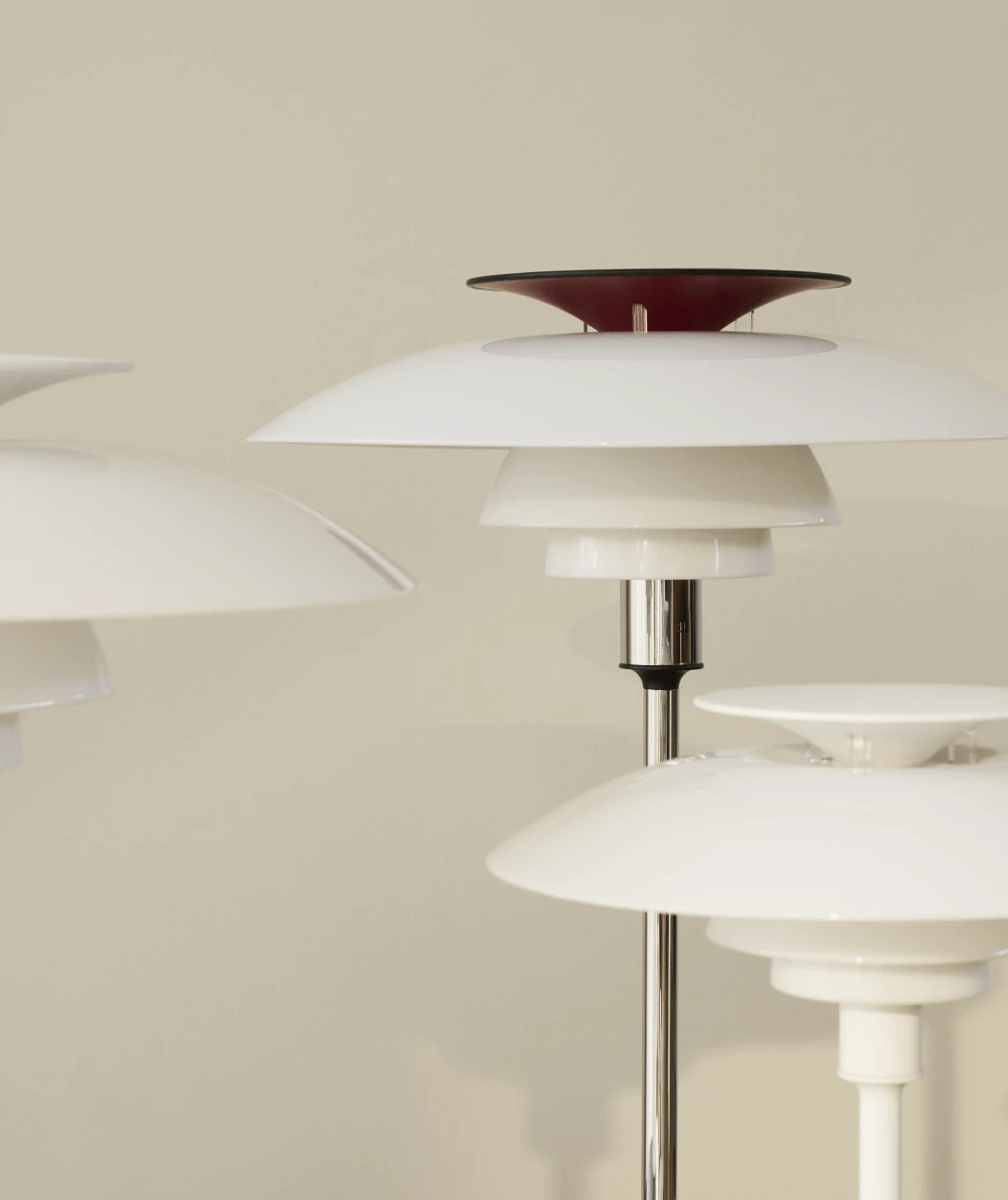 Close-up van PH 80 Portable in White Opal met chromen steel tegen beige muur, © 2025 Louis Poulsen.
