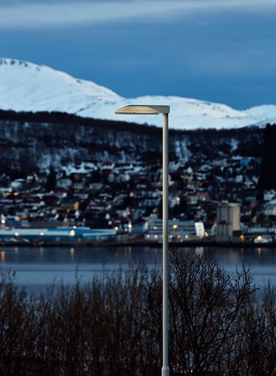 An LP Xperi outdoor light overlooks Tromsø’s waterfront, with snow-covered mountains in the background. © 2026 Louis Poulsen.