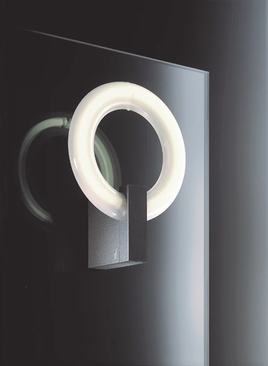 An LP Icon Wall Lamp with a glowing white ring and dark mount against a dark wall. © 2026 Louis Poulsen.
