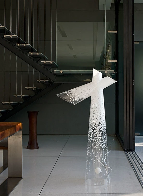 A clear sculptural award with white details stands in a modern foyer beside a staircase. © 2026 Louis Poulsen.