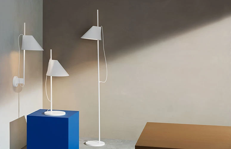 White Yuh Wall Lamp, Yuh Table Lamp and Yuh Floor Lamp arranged against a light wall. © 2026 Louis Poulsen.