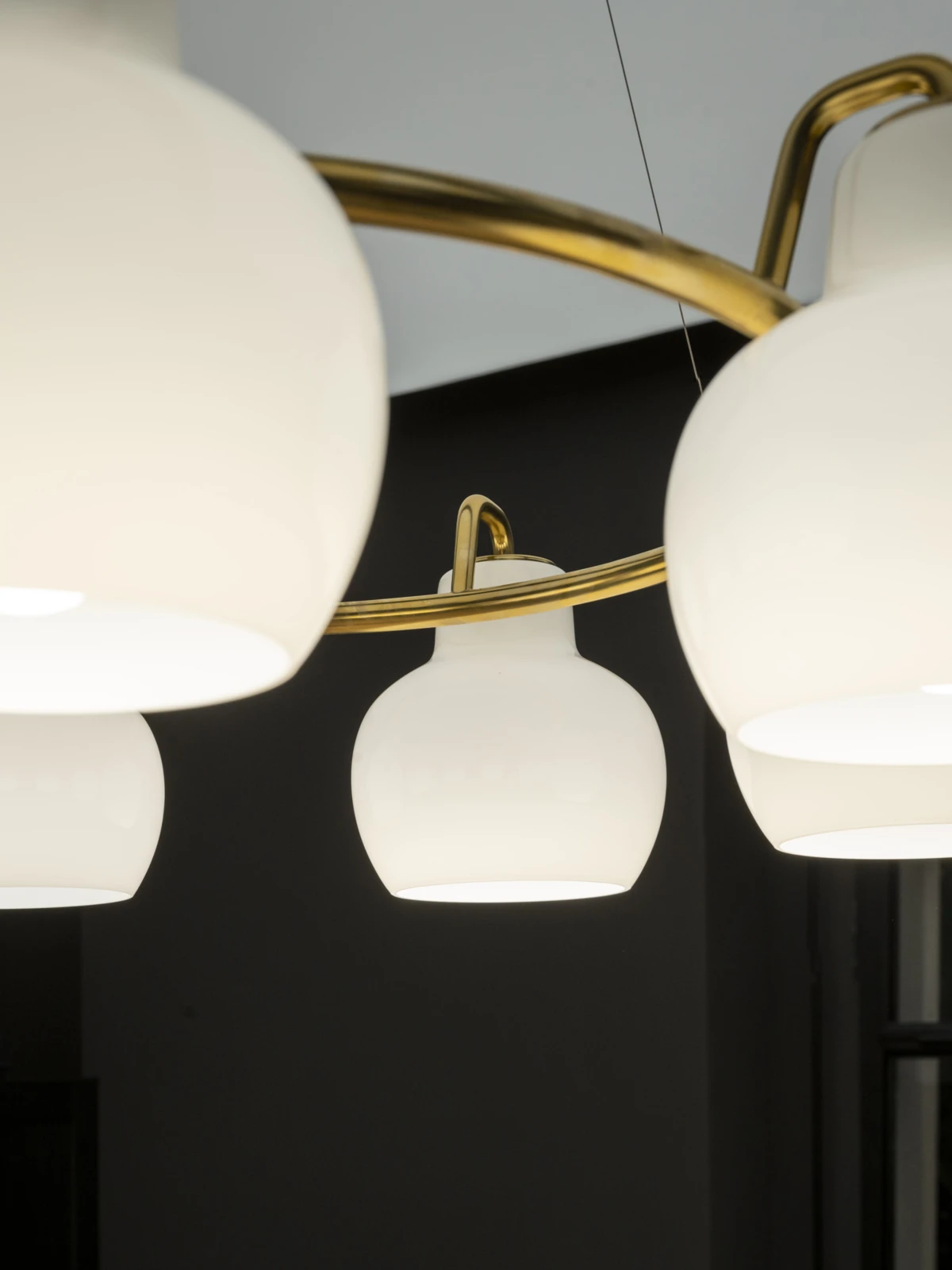 VL Ringcrown pendant with white globes and brass accents against a dark background, © 2025 Louis Poulsen.