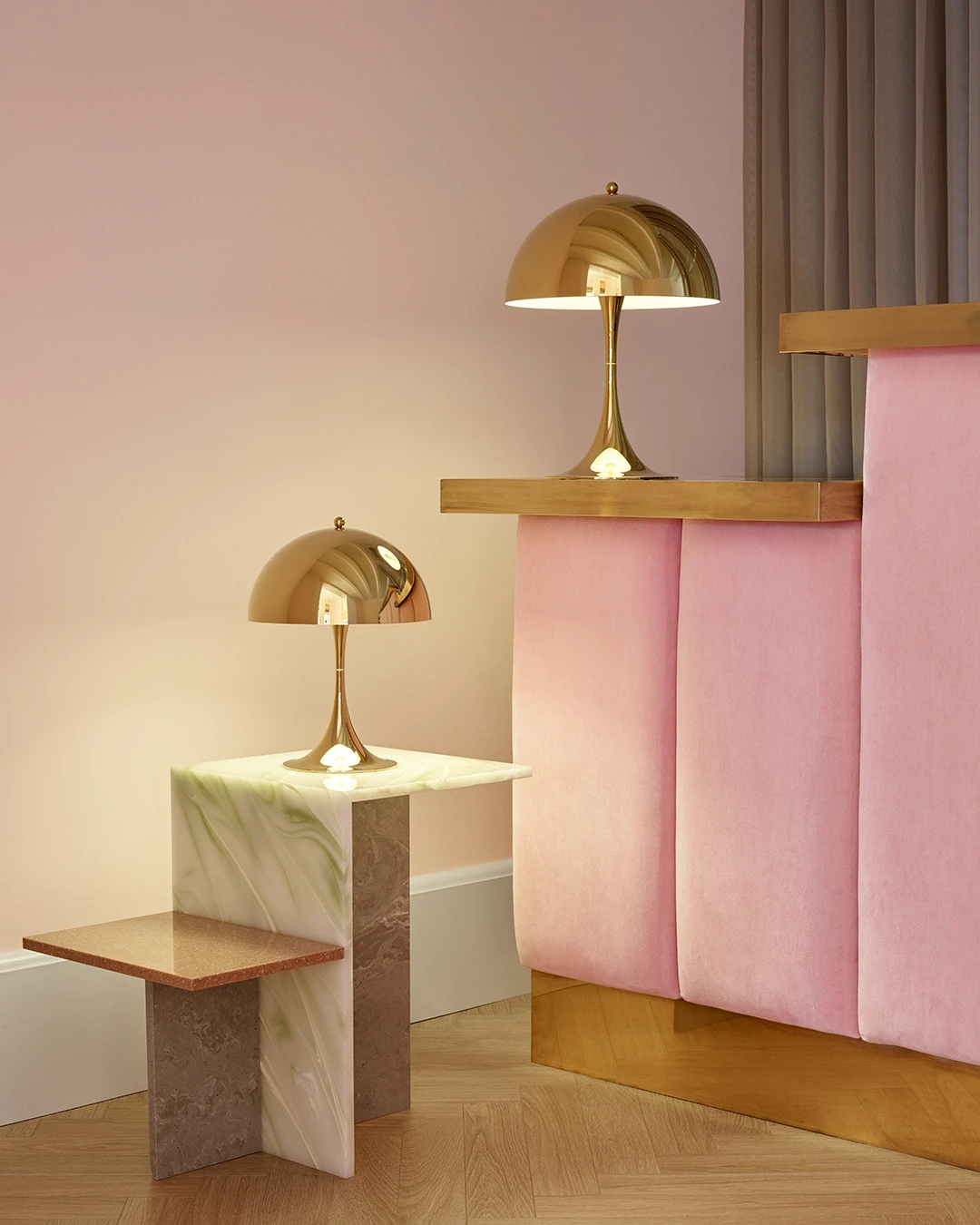 Panthella 320 and 250 brass table lamps on a marble and wood side table, © 2025 Louis Poulsen.