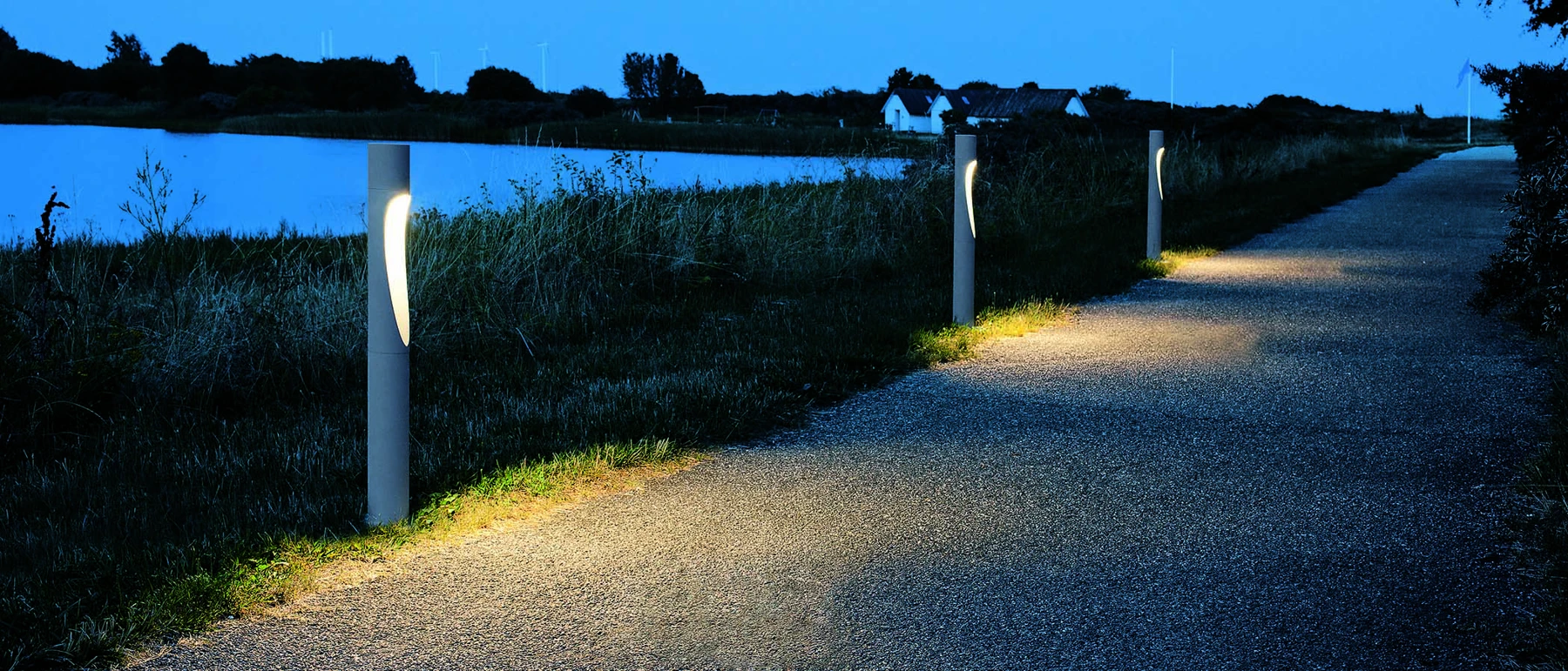 Flindt Bollard lights illuminate a waterside path in Vallensbæk at dusk. © 2026 Louis Poulsen.