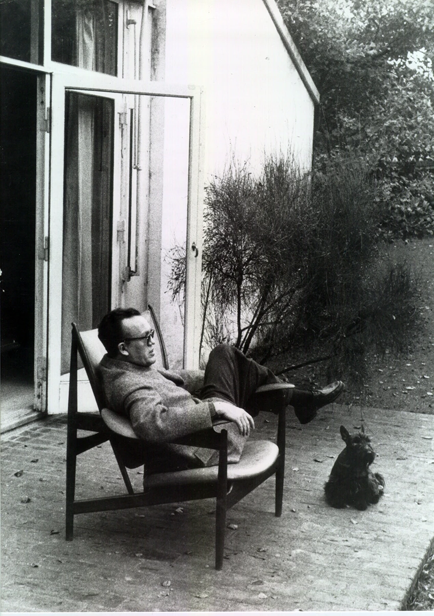 Finn Juhl relaxing with a dog outside, © 2025 Louis Poulsen.