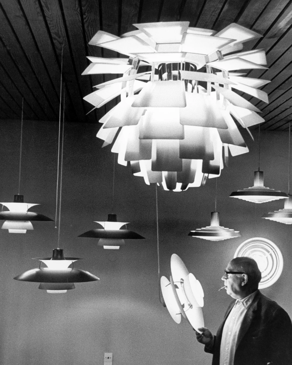 Poul Henningsen bekijkt Artichoke en PH lampen in showroom, © 2025 Louis Poulsen.
