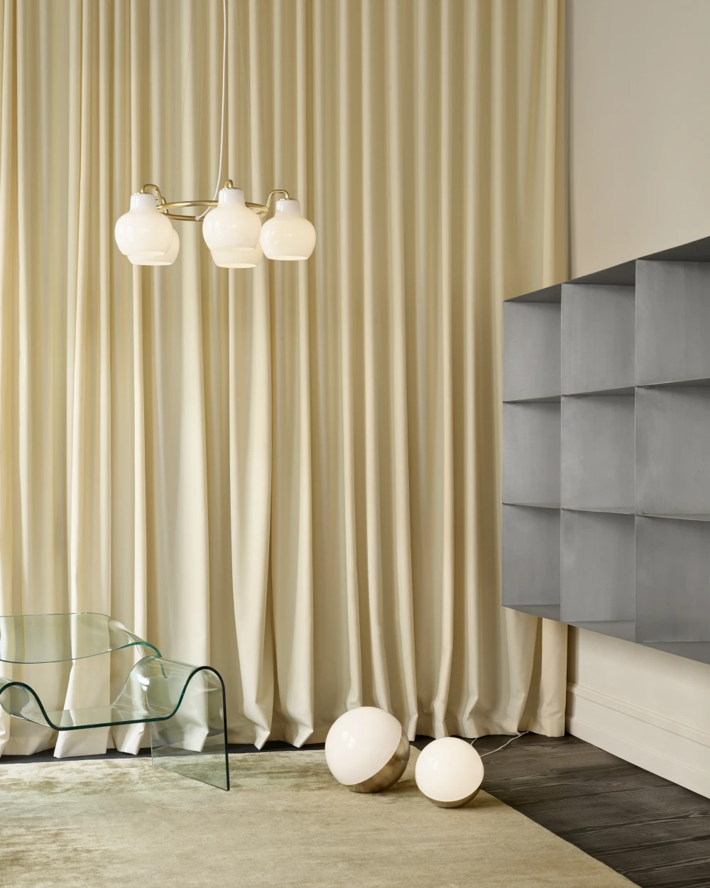 A VL Ring Crown 3-5-7 Pendant with opal glass shades hangs above a glass table, with VL 45 Radiohus Portable Lamps on the floor. © 2026 Louis Poulsen.