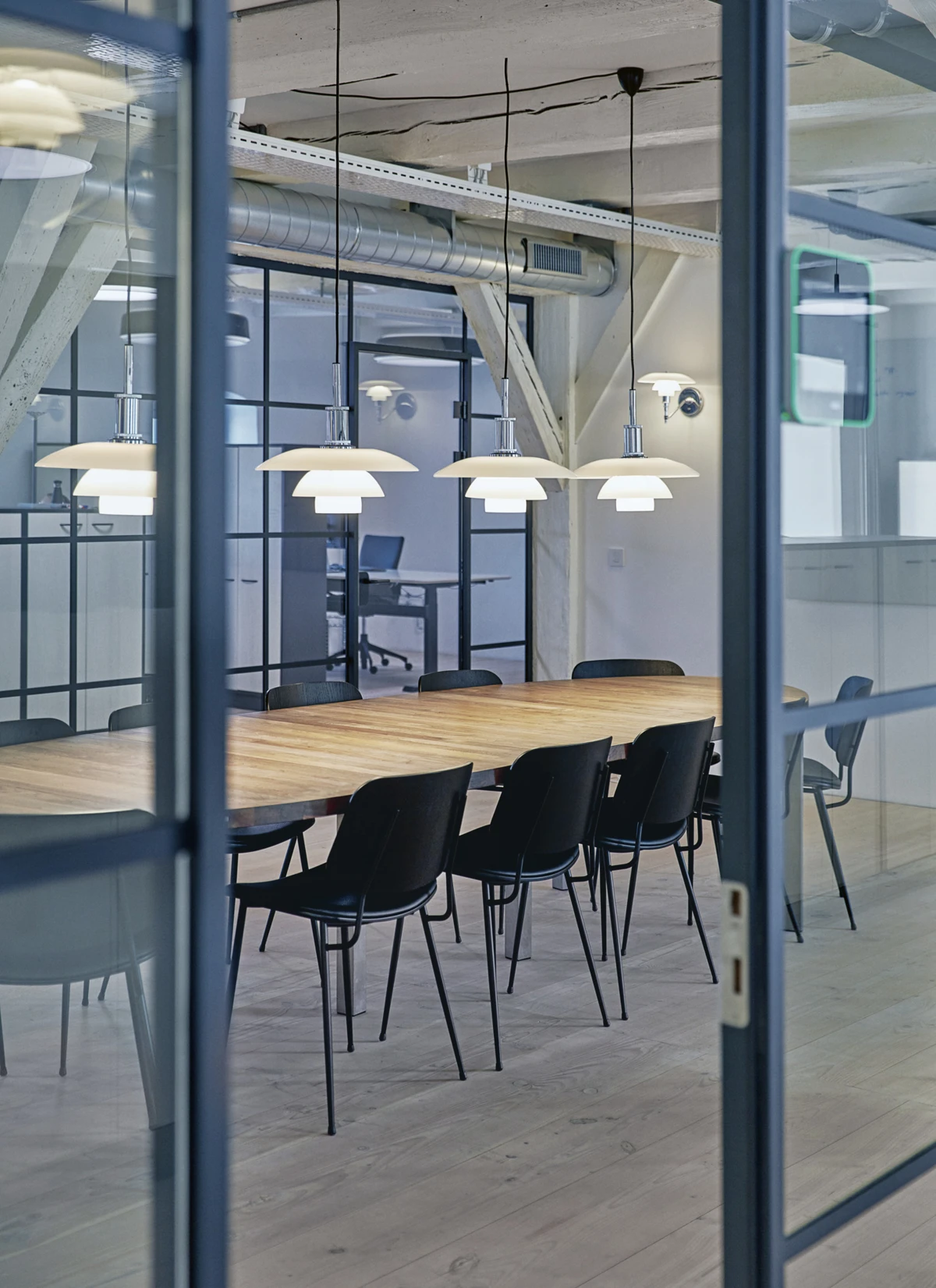 PH 4½-4 Pendants light a long wooden table in Louis Poulsen’s Kuglegaarden showroom in Copenhagen. © 2026 Louis Poulsen.