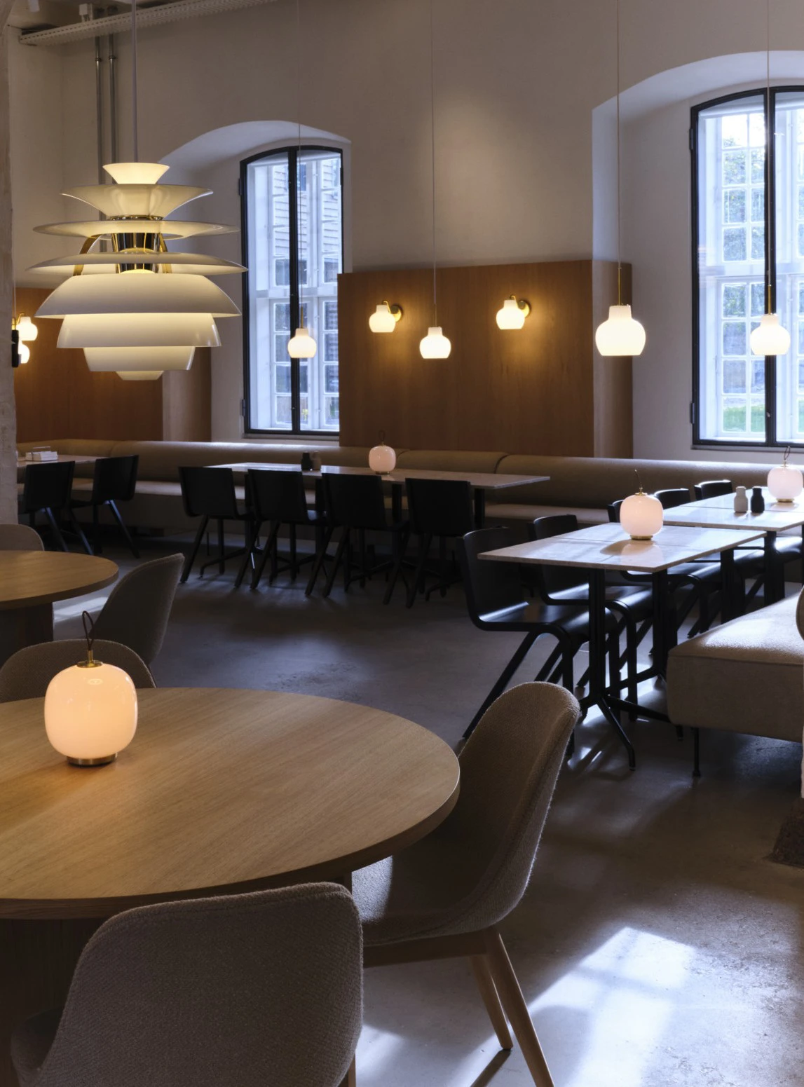A white PH Artichoke hangs over the dining area, with VL 45 Radiohus Pendants and Panthella 160 Portable Lamps. © 2026 Louis Poulsen.