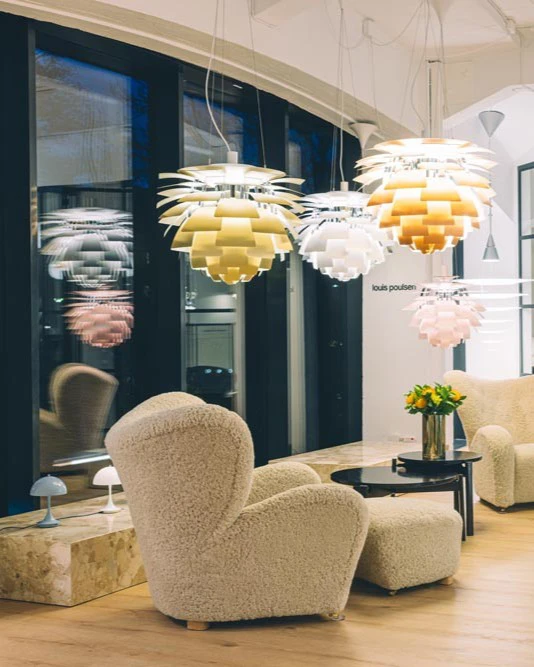 PH Artichoke pendants in gold, white and pink hang above lounge seating in the Oslo showroom. © 2026 Louis Poulsen.