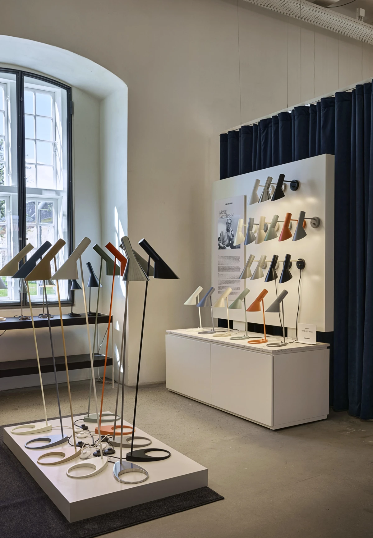 AJ table, floor and wall lamps in multiple colours displayed inside the Louis Poulsen Copenhagen showroom, © 2025 Louis Poulsen.