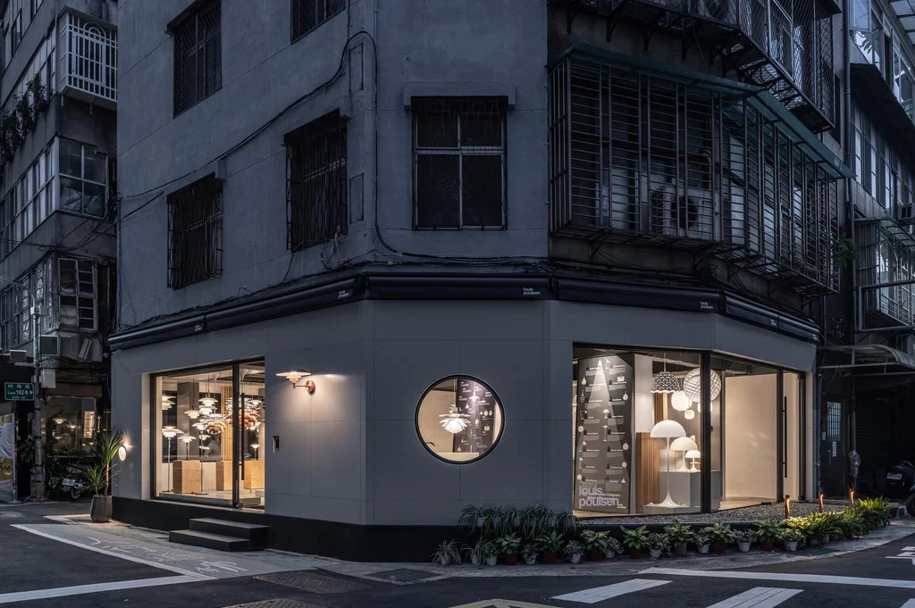 The Louis Poulsen store in Taipei glows at dusk, with pendants and table lamps in the windows and a PH 2/1 Wall Lamp beside the entrance. © 2026 Louis Poulsen.