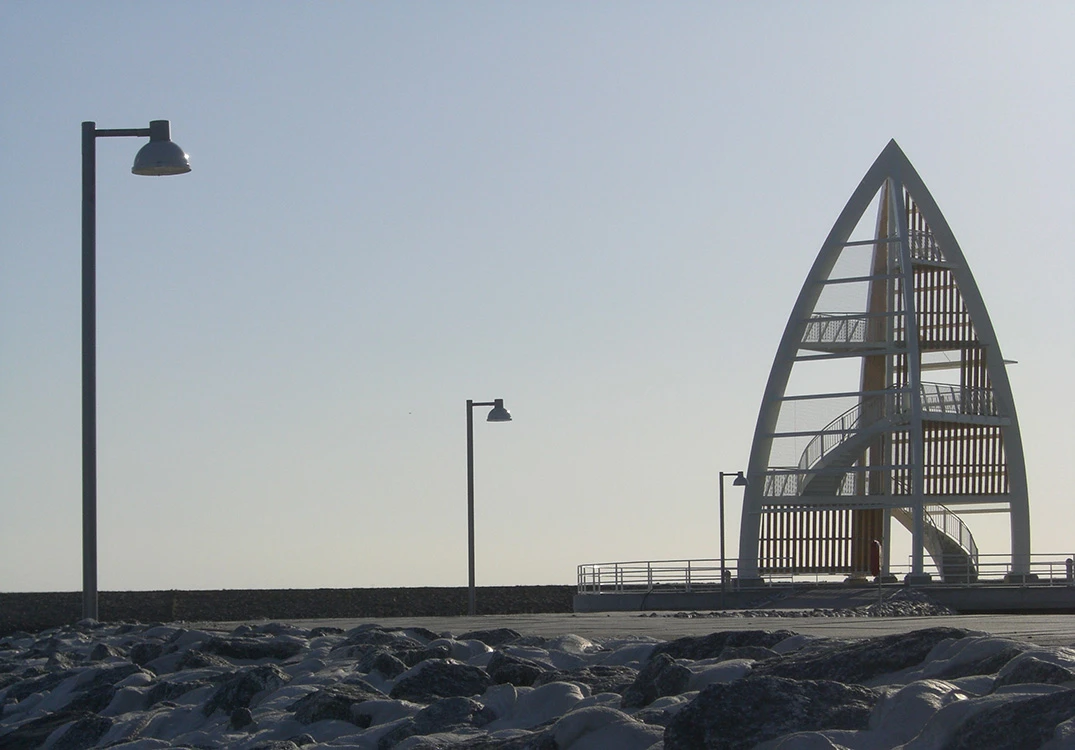 Albertslund Maxi Post lights the rocky pier on Juist, with a sculptural observation tower rising behind it. © 2026 Louis Poulsen.