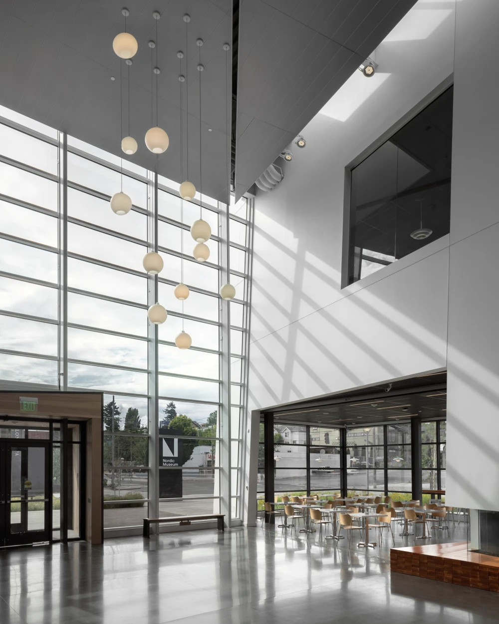 VL 45 Radiohus-pendels van opaalglas hangen op verschillende hoogtes in het lichte atrium van het Nordic Museum. © 2026 Louis Poulsen.