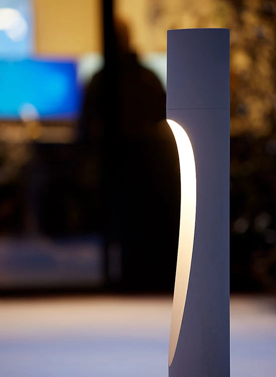 A dark grey Flindt Bollard casts a warm glow outside the Nortvig headquarters at dusk. © 2026 Louis Poulsen.