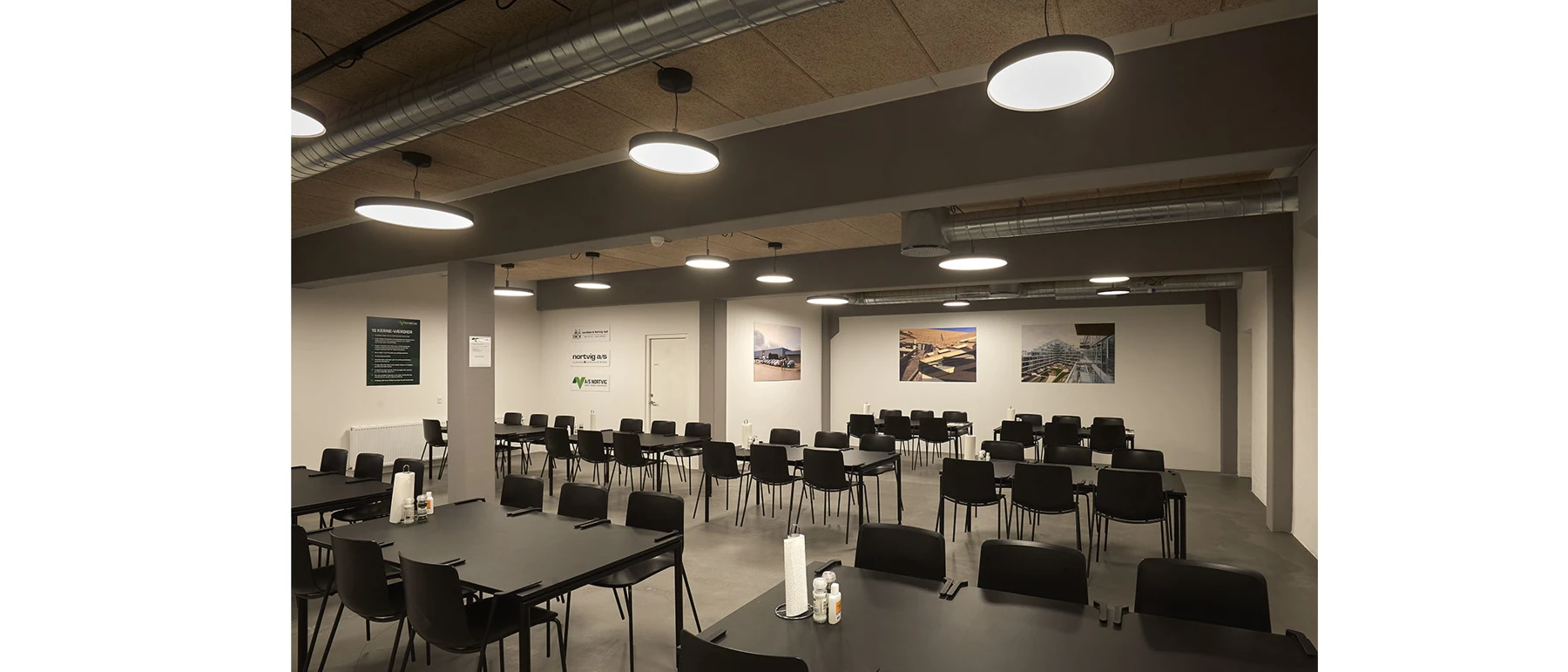LP Slim Round Suspended luminaires light an office with rows of tables and black chairs. © 2026 Louis Poulsen.