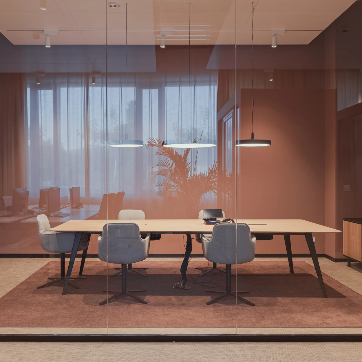 LP Slim Round Suspended pendels boven een vergadertafel in een modern kantoor met glazen wanden. © 2026 Louis Poulsen.