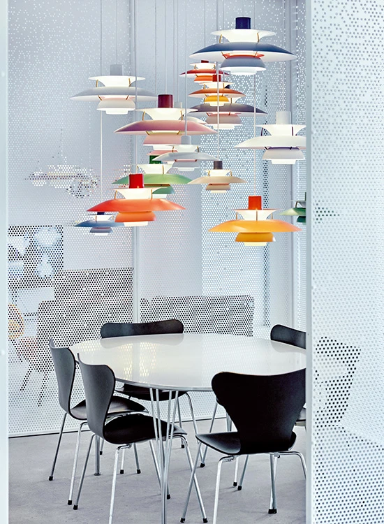 Colourful PH 5 pendants hang above a white meeting table in Louis Poulsen’s Copenhagen showroom. © 2026 Louis Poulsen.