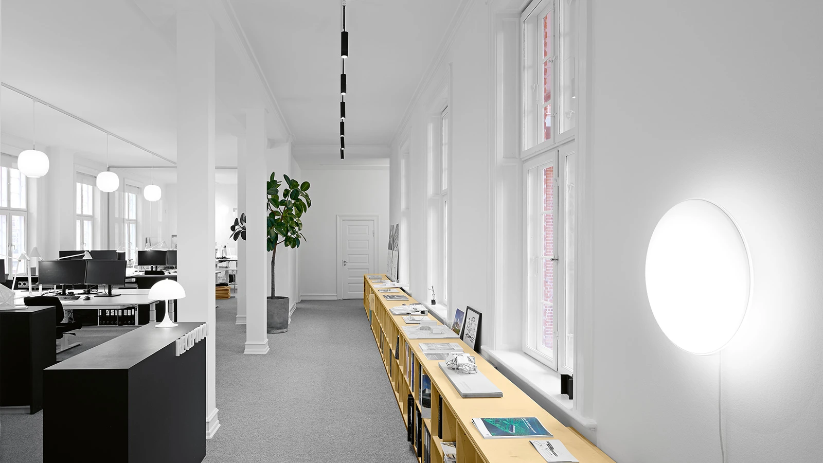 A Ripls wall lamp glows in a bright office with VL 45 Radiohus Pendants and a Panthella 250 Table Lamp. © 2026 Louis Poulsen.