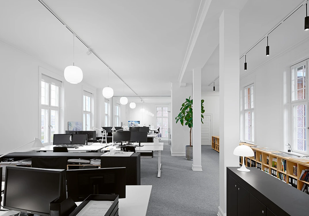 Weiße VL 45 Radiohus Pendelleuchten und eine Panthella 250 Tischleuchte in einem hellen Architekturbüro. © 2026 Louis Poulsen.