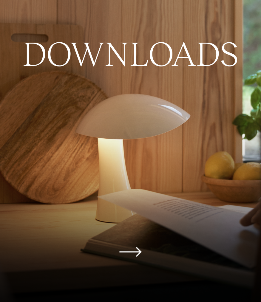 Downloads: een witte Panthella 250 Portable Lamp geeft licht op een houten werkblad. © 2026 Louis Poulsen.