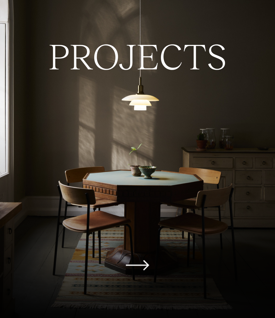 En vit PH 3½-3-pendel över ett matbord i ett dunkelt rum, med texten ”Projects”. © 2026 Louis Poulsen.