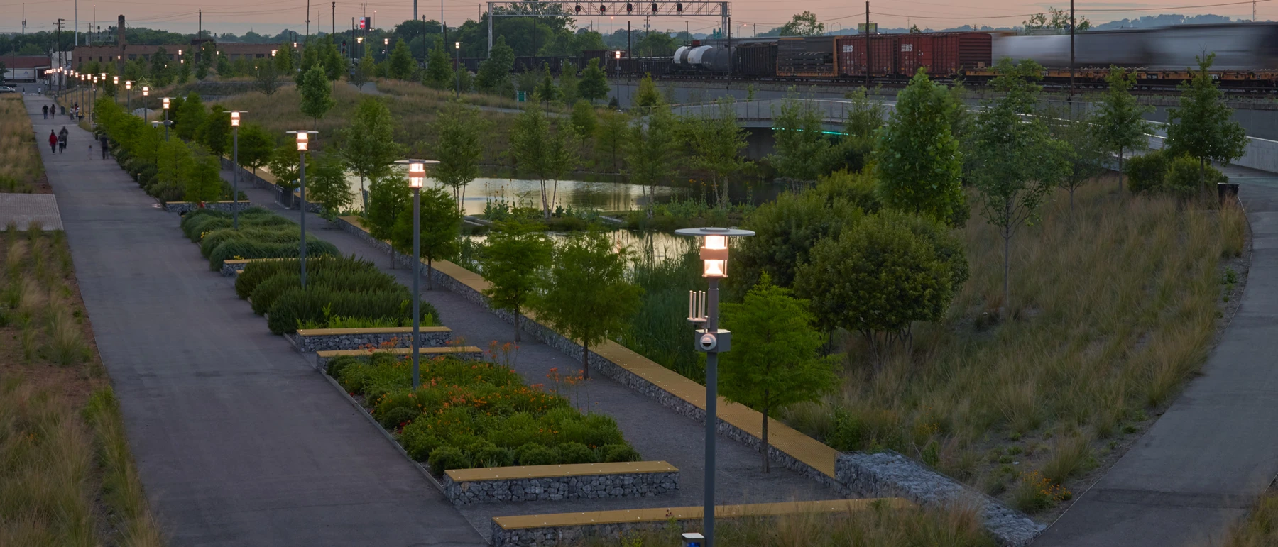 Kipp Bollard lights line a path through Railroad Park, surrounded by planting at dusk. © 2026 Louis Poulsen.