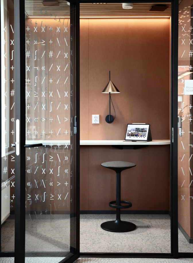 A Keglen Wall Lamp with a metallic shade and black wall mount in a compact work nook. © 2026 Louis Poulsen.