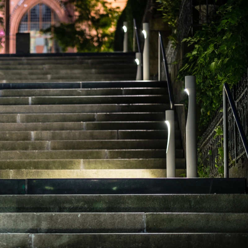 White Flindt Bollard lights illuminate outdoor steps beside a building at night. © 2026 Louis Poulsen.