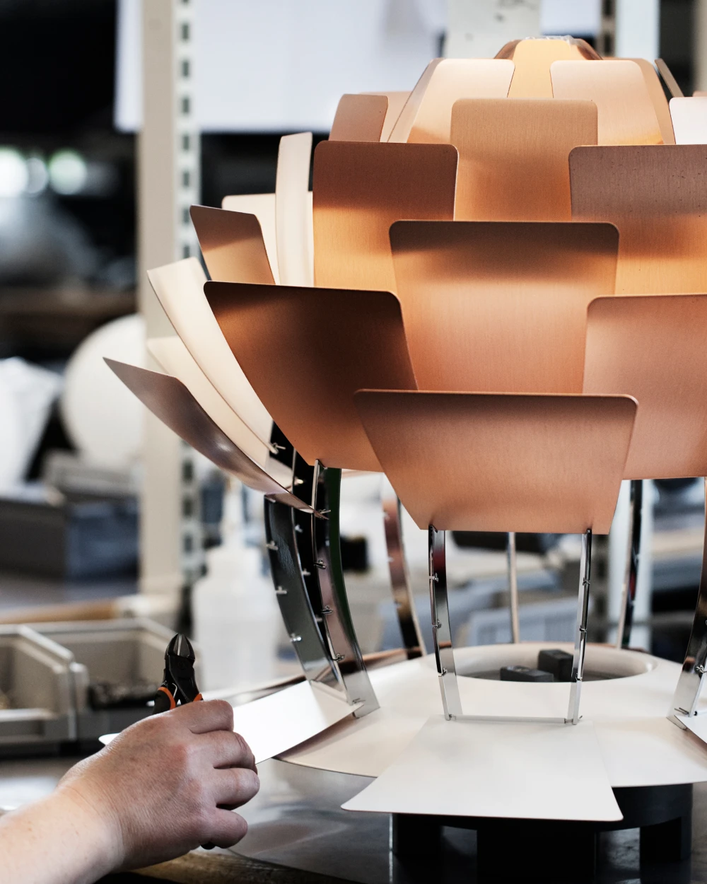 A copper PH Artichoke pendant being assembled in a workshop. © 2026 Louis Poulsen.