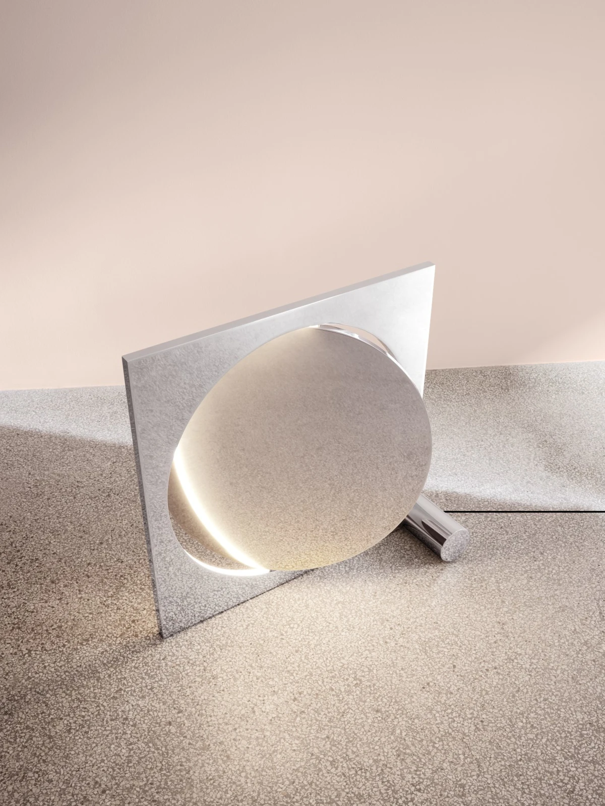 The polished metal Moonsetter floor lamp stands on a terrazzo floor against a pale pink wall. © 2026 Louis Poulsen.