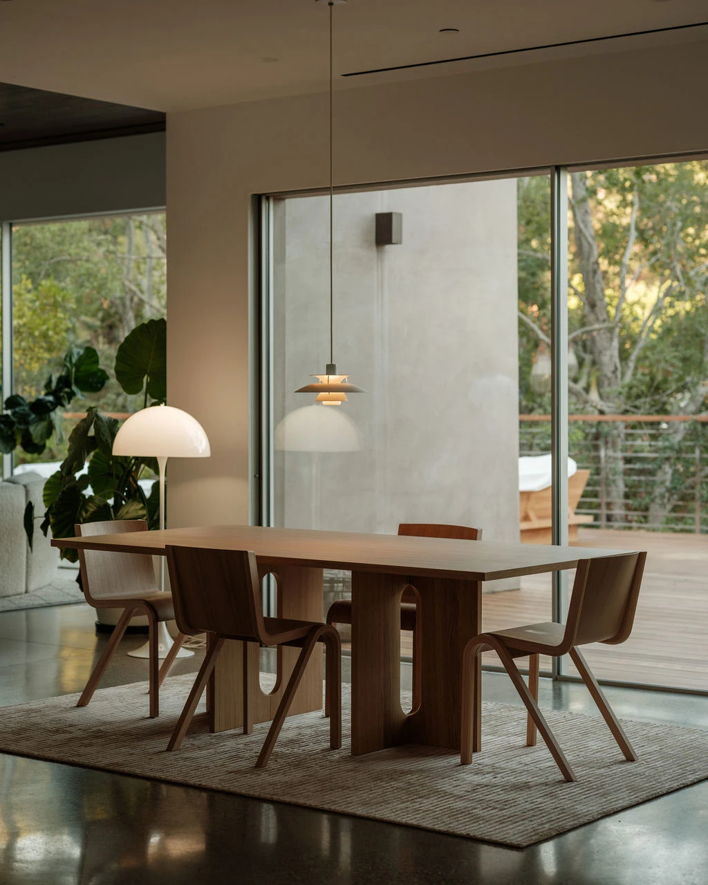 A white Panthella 400 Table Lamp and a PH 3/3 Pendant above a wooden dining table beside large windows. © 2026 Louis Poulsen.