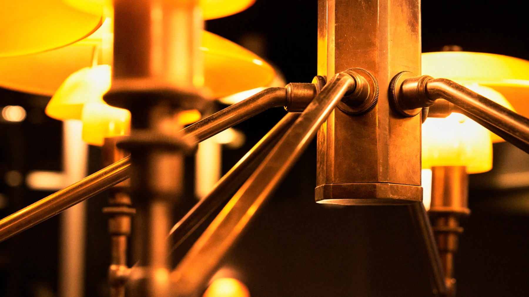 Close-up of the brass PH 1/1 Chandelier Centenary Edition, with its shades glowing warmly. © 2026 Louis Poulsen.