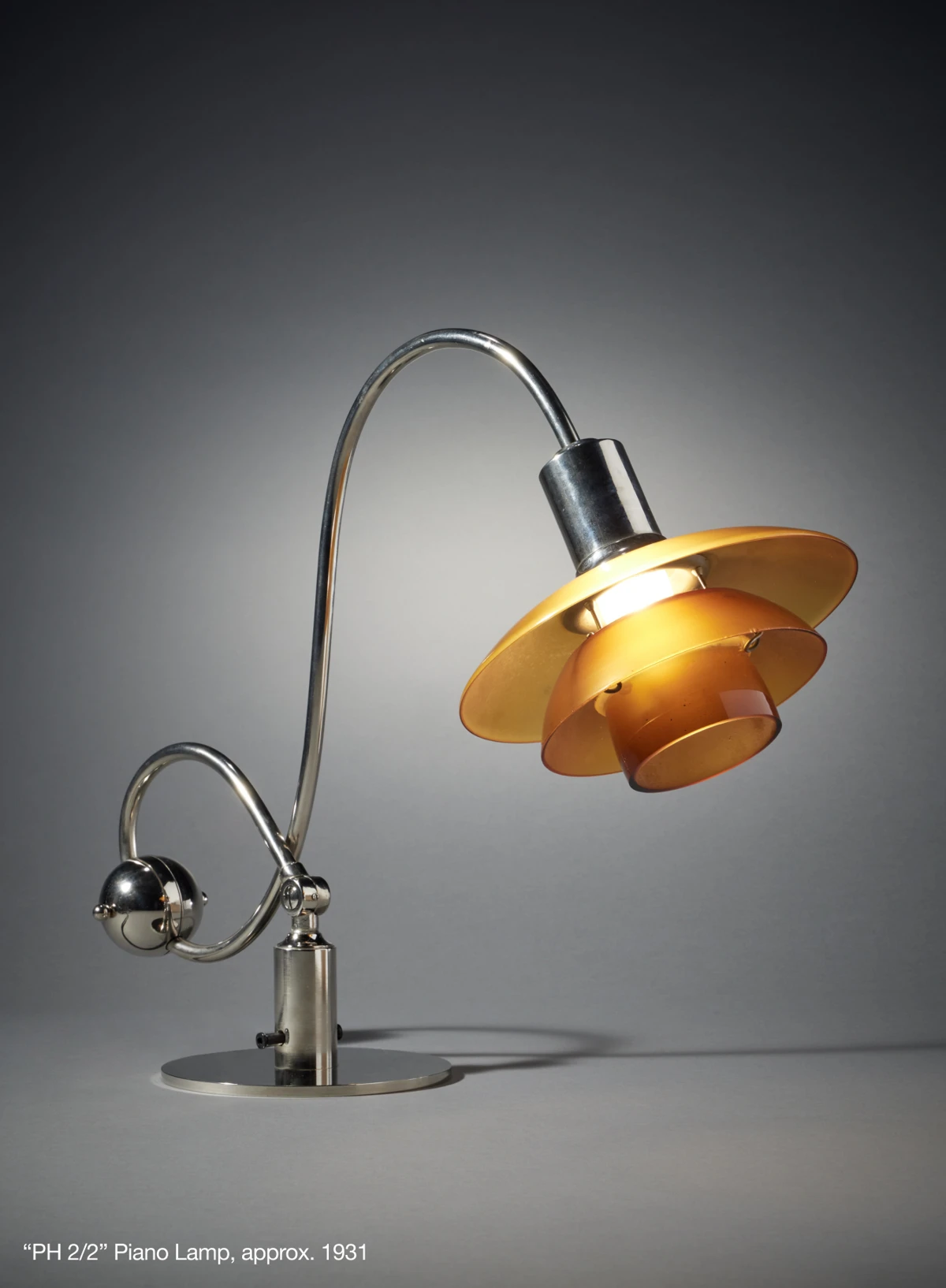 PH 2/2 Question Mark Table Lamp in chrome with amber-coloured shades, shown against a grey background. © 2026 Louis Poulsen.