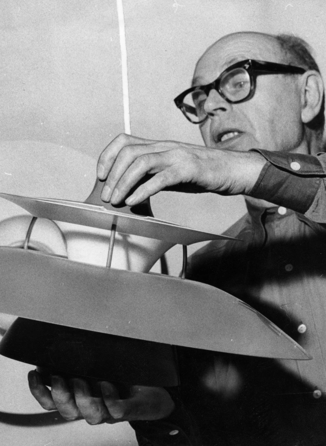 Poul Henningsen examines a PH 5 pendant in a historic black-and-white photograph. © 2026 Louis Poulsen.