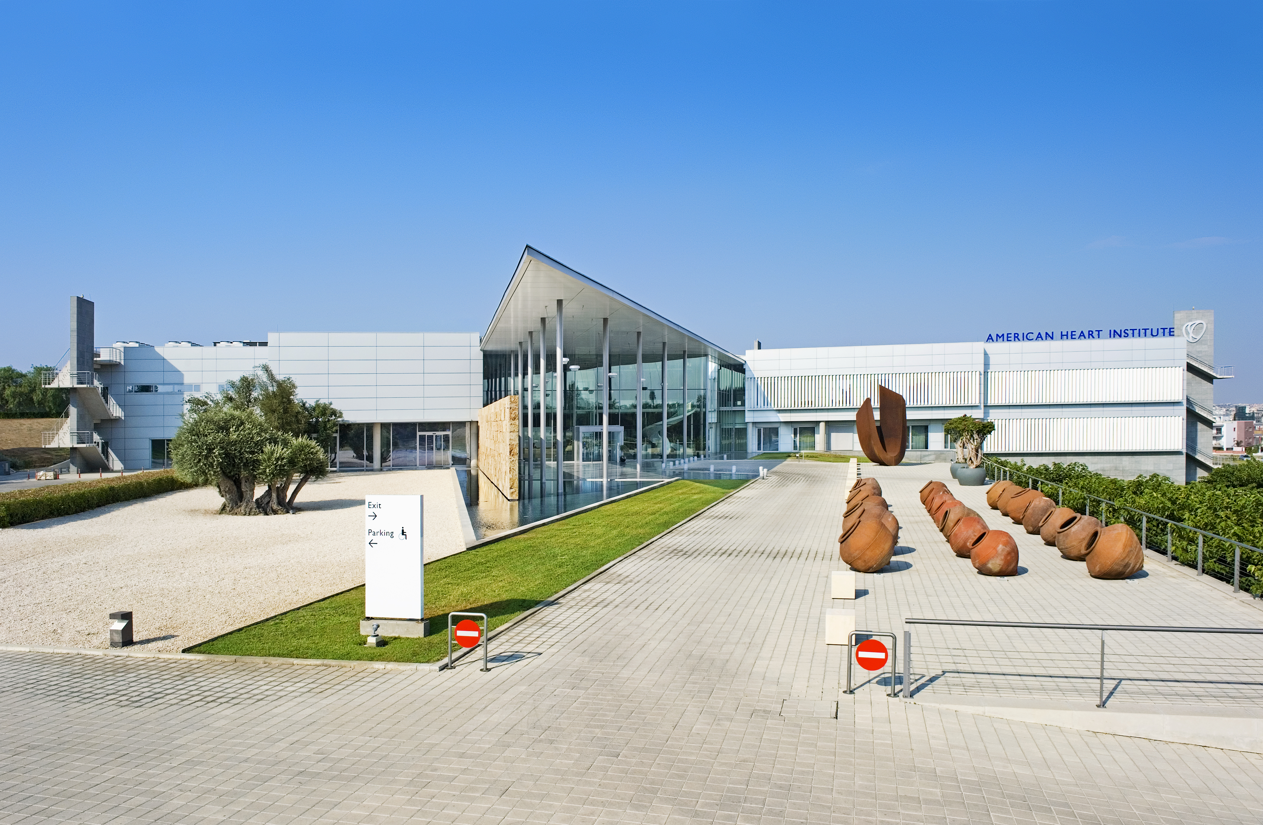 The American Heart Institute in Cyprus, with a modern white facade, glass entrance and broad paved forecourt. © 2026 Louis Poulsen.