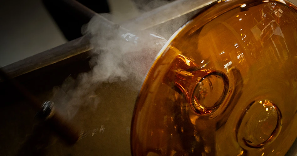 Nærbillede af den ravfarvede glasskærm på PH 2/1 Amber Coloured Glass Table Lamp under fremstillingen. © 2026 Louis Poulsen.